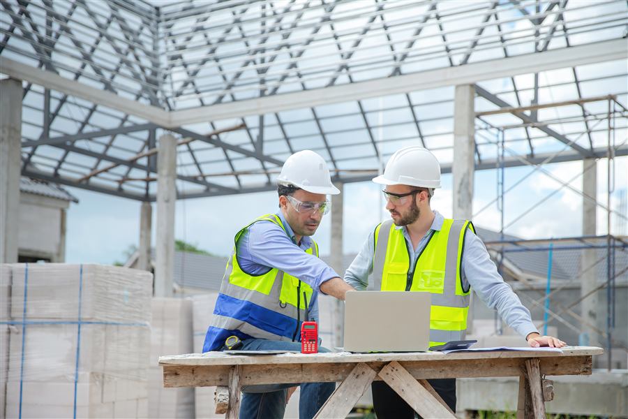 Ingenieros revisando un modelo estructural en laptop durante una visita de obra